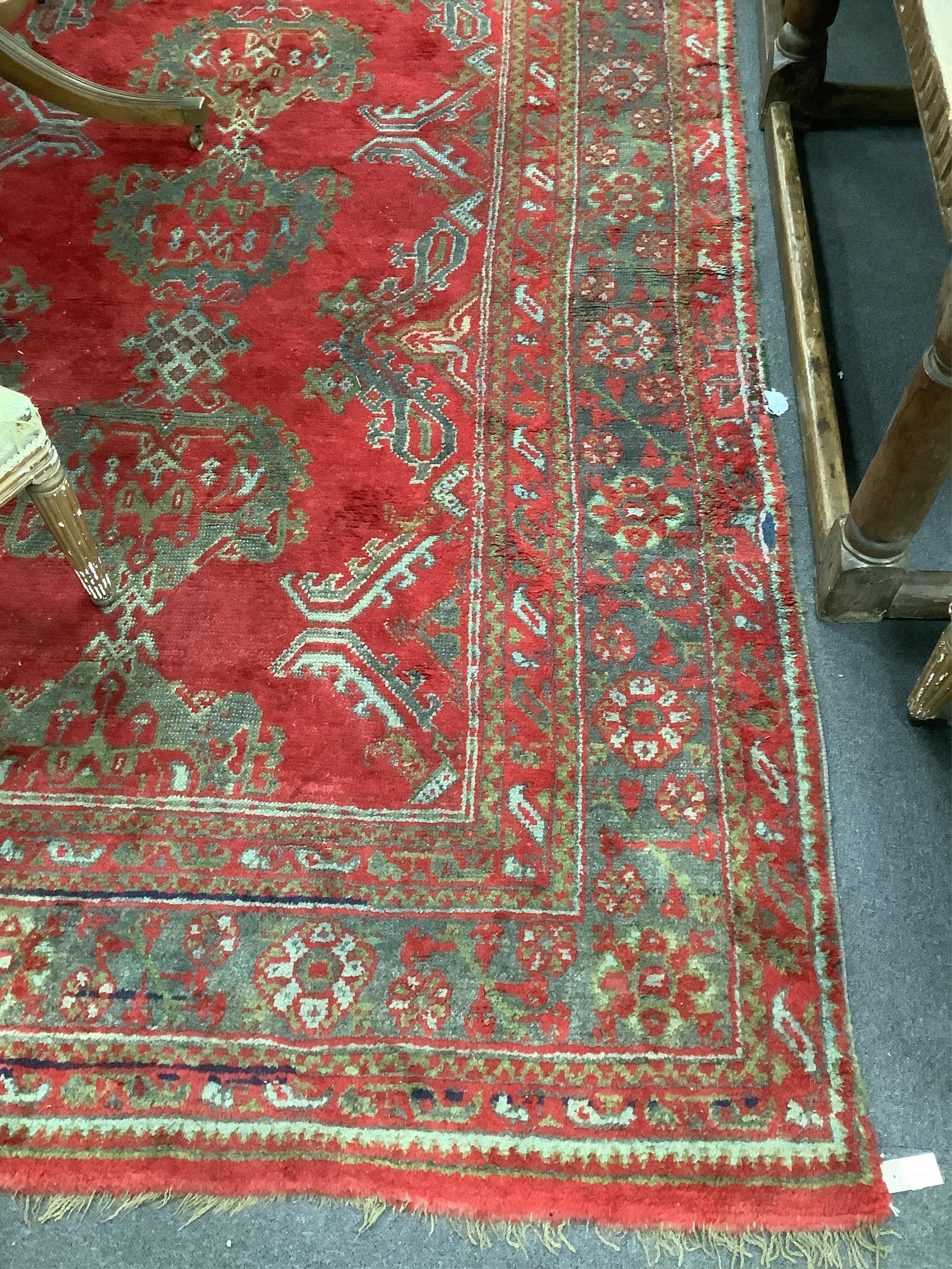 A large Turkish carpet, with triple row of stylised medallions on a red ground, multi bordered, 413 x 345cm. Condition